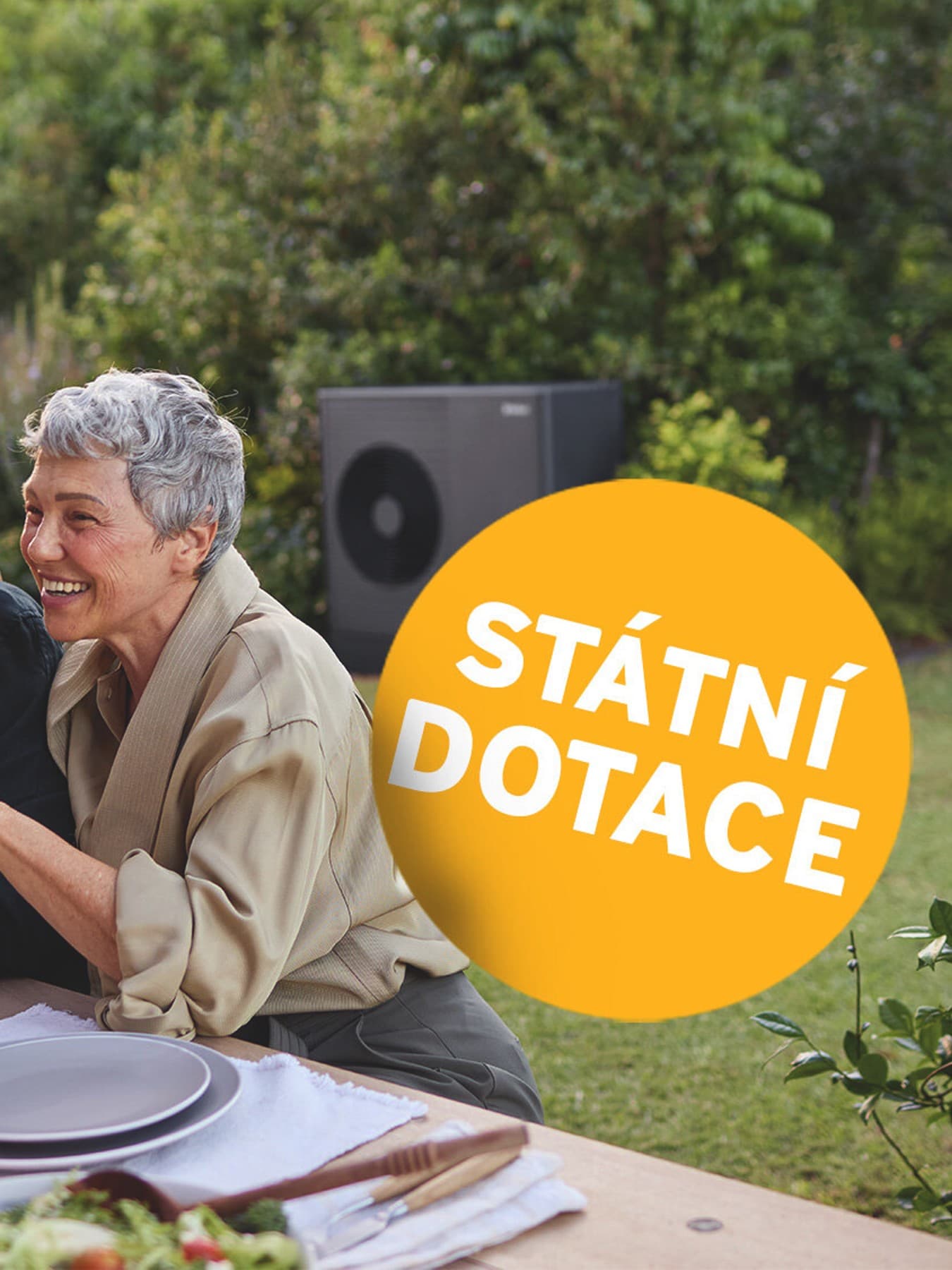 Pár sedící na zahradě, vedle nich plovoucí tlačítko s doporučením zajistit si dotace.